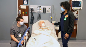 Patient in bed with two VA nurses beside him