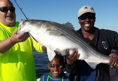 Woman, her son, and a man hold a large fish.