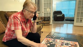 Senior woman talking on the phone while doing jigsaw puzzle