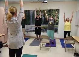 A group of Veterans engaging in yoga with a VA instructor 