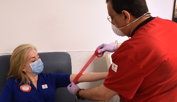 Technician preparing volunteer for blood donation
