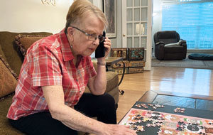 elder woman sitting on sofa doing jigsaw puzzle