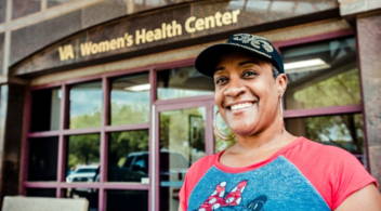 A smiling woman in front of a VA Women's Health Center