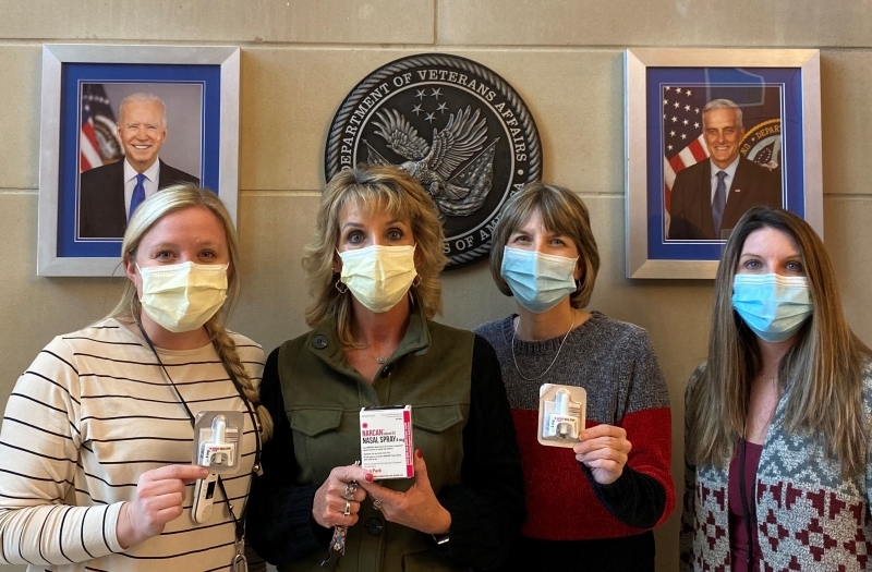 Four women in medical masks holding medical supplies