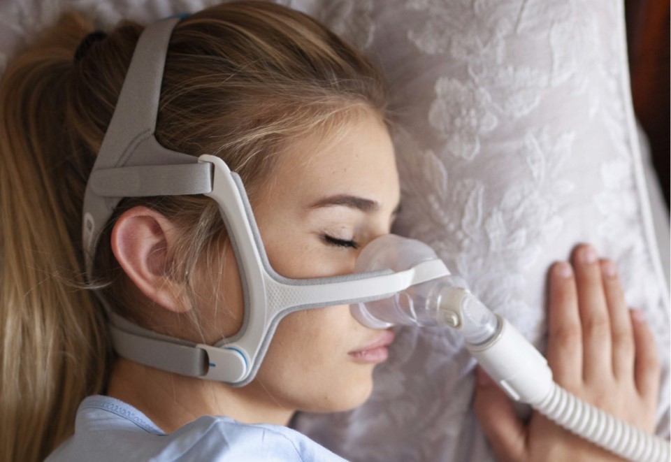 Woman sleeping in a continuous positive airway pressure (CPAP) mask 