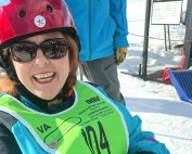 A woman wearing a helmet smiles against a snowy background