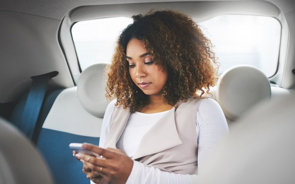 young woman in back seat of car using phone