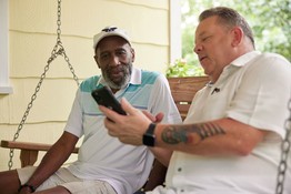 Man showing features of program on phone to Veteran