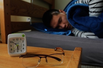 Alarm clock on bedside table near Veteran sleeping  