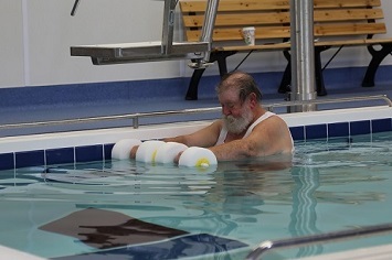 Veteran exercising with floating weights in the swimming pool  