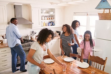Veteran cooking while family sets the table for dinner 