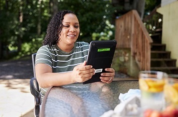 Veteran seated at a patio table using Mental Health Checkup app on a tablet device