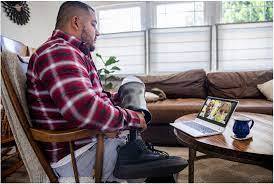 man with prosthetic feet sitting and holding a video conference on a laptop