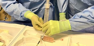Doctors' hands preparing surgical catheter