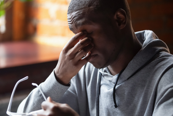 A Veteran pinching the bridge of his nose in pain 