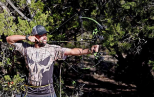A man outdoors pulling back a compound hunting bow