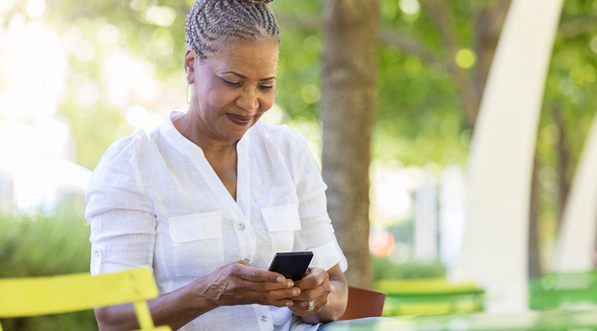 A woman sitting outside using her smart phone