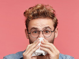 Young man with a tissue to his nose.