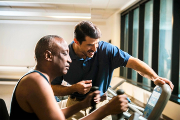 A Veteran working out while his physical therapist monitors his heart rate on the screen