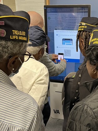 Group of Veterans around the VA Wayfinding kiosk