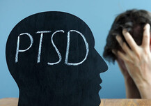 PTSD concept image with model of head and man with head in hands.