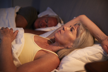 Veteran in bed staring at the ceiling next to her sleeping partner