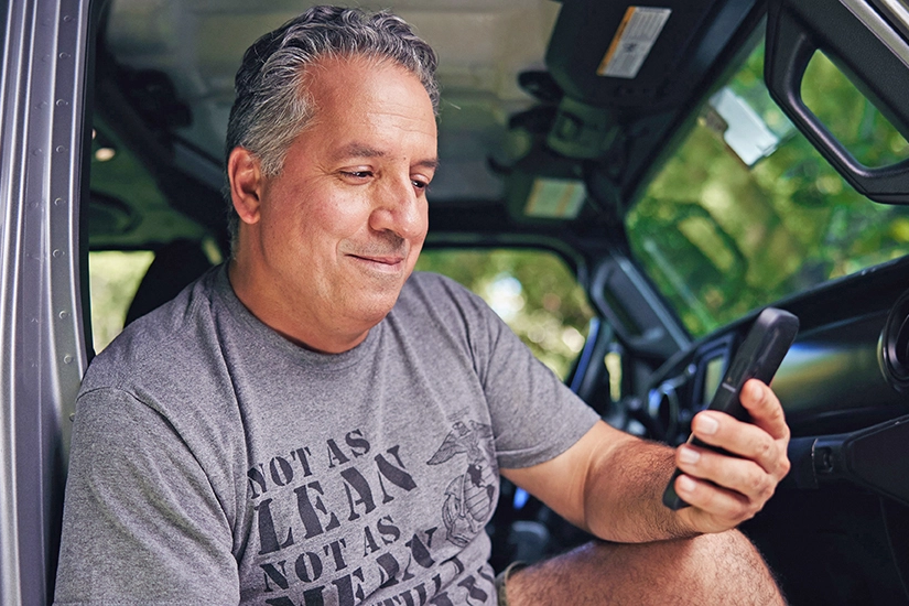 A Veteran checking his phone in the passenger seat of a vehicle