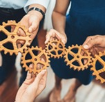 People holding gears that fit together, symbolizing teamwork
