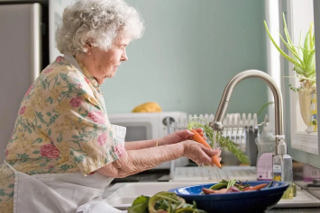 A Veteran washing vegetables in her kitchen