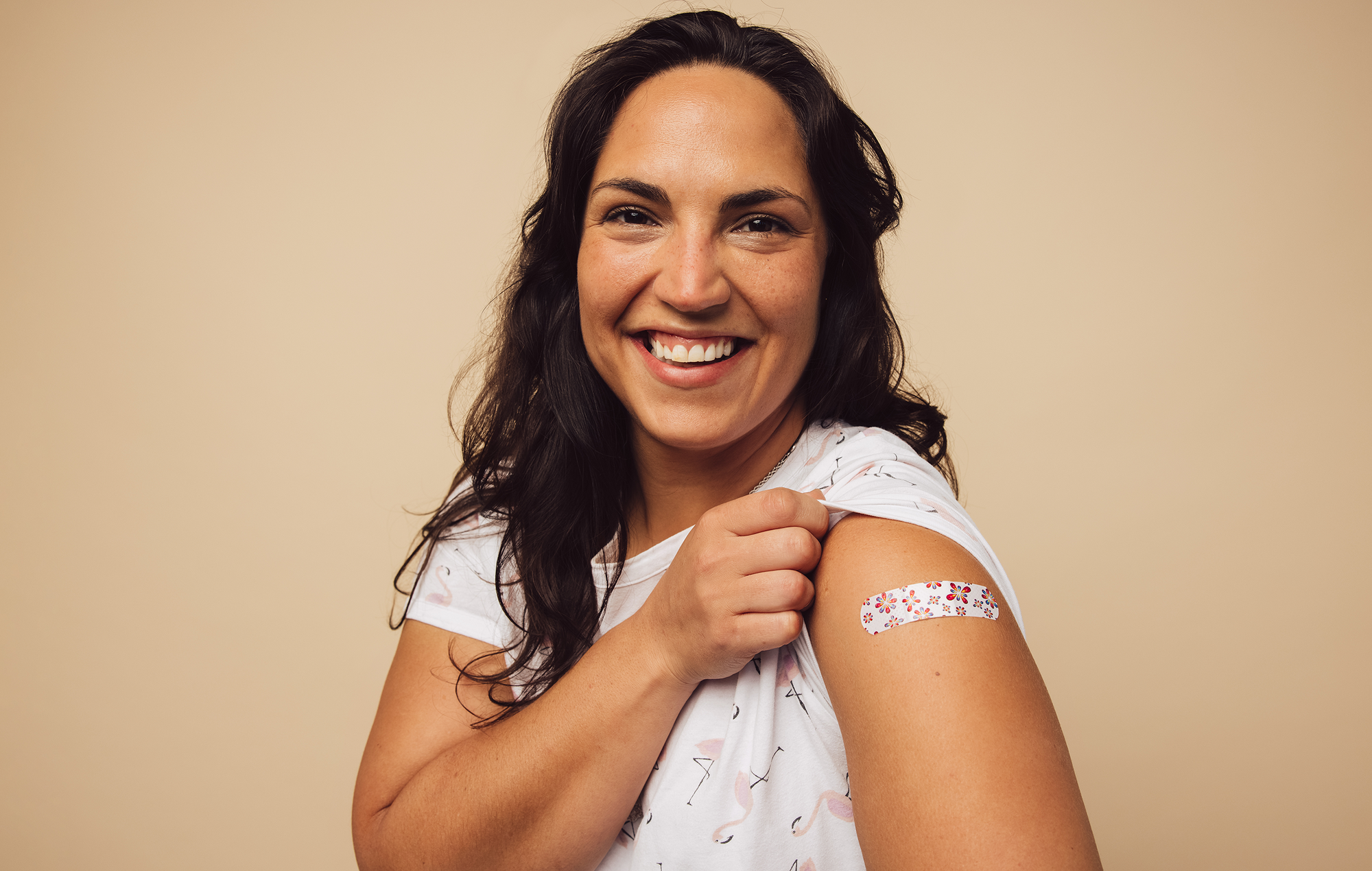 Hispanic woman with a bandage on her arm from a vaccination.