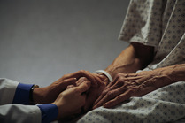 Healthcare worker holding hands of elderly patient 