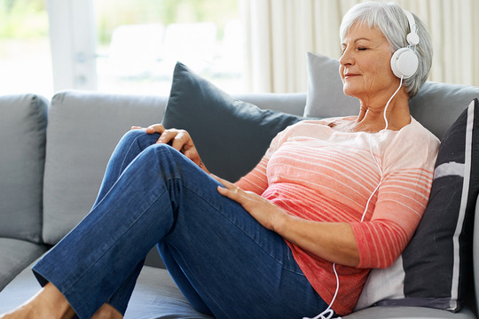 Woman sitting on couch with headphones on