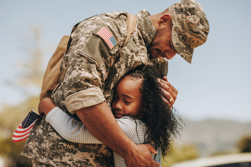 Soldier in fatigues hugging child