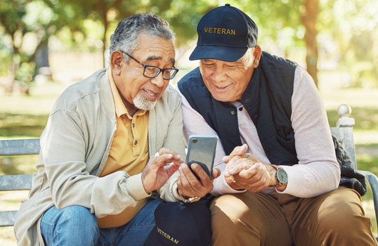 Two elder Veterans looking at a cell phone