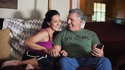 Happy couple sitting together on the sofa while looking at a smartphone