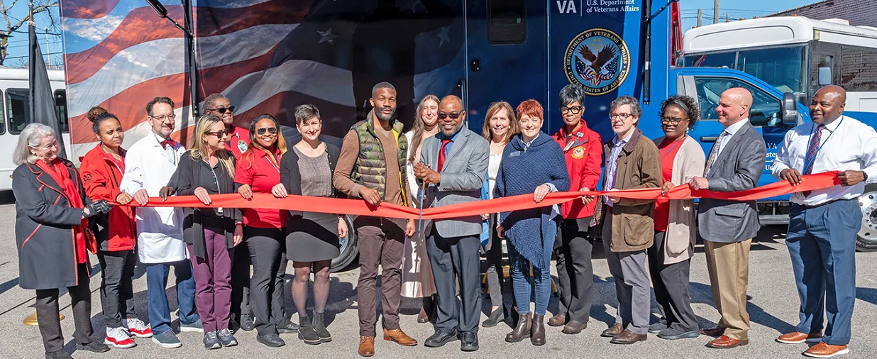 a group of diverse individuals cutting a ribbon