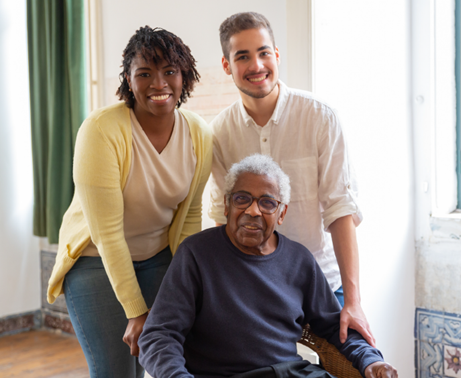 2 young caregivers and an elderly man smile.