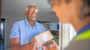 An older man is receiving a box delivered to his home