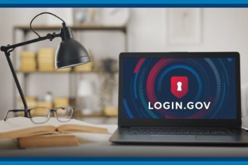 A laptop on a desk displays Login.gov.