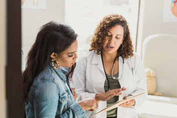 A medical professional reads from a chart to a person.