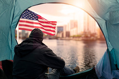 Homeless man sitting in tent looking out at the city.