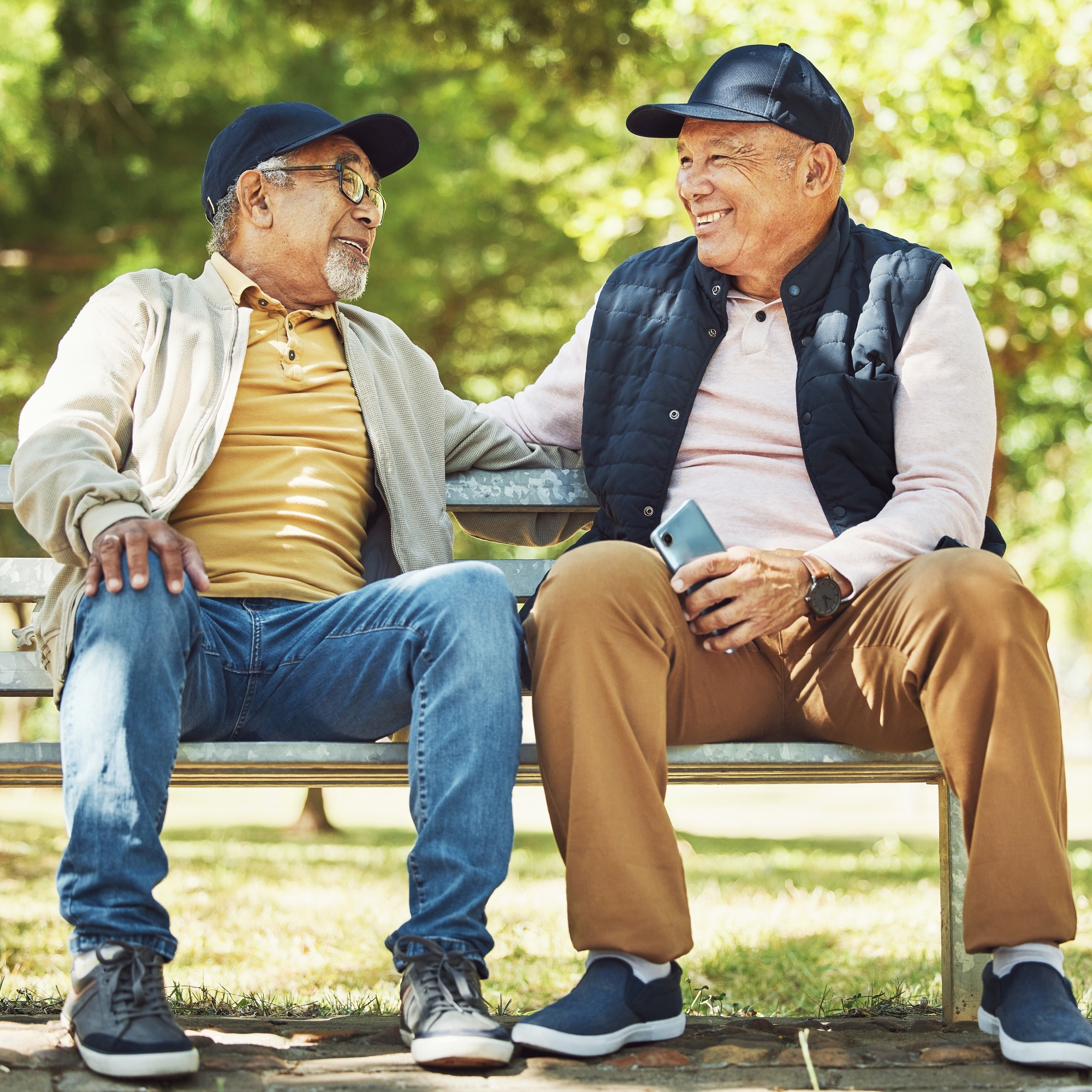  Two older men seated on a park bench, enjoying a peaceful moment amidst the greenery and natural surroundings.