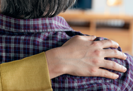 Older person being comforted with a arm over their shoulders.