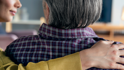 Older person being comforted with a arm over their shoulders.