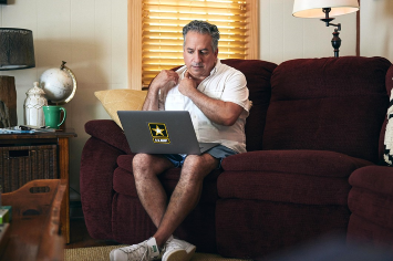 A person sits on a couch while using a laptop.