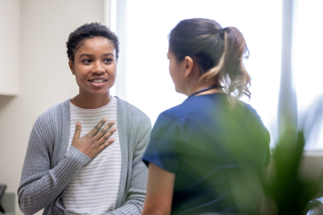 A person holds their chest while speaking with a medical professional.