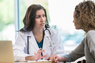 A medical professional sits and shares information to a person.