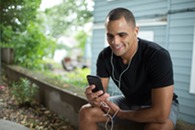 A person holds their phone with headphones on.
