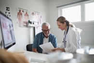 A person sits down in a medical office while a doctor goes over health information.