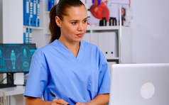 Doctor assistant in uniform working on laptop.